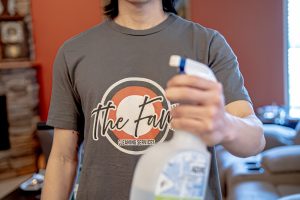 cleaner with company shirt holding spray bottle